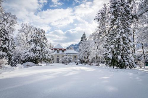 a house covered in snow in front of trees at Galerie Hotel in Bad Reichenhall