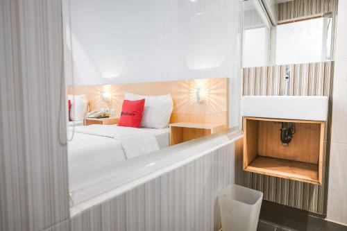 a hotel room with a bed with red pillows at RedDoorz Premium at Hotel T-ONE Jambi in Tanjungjohor