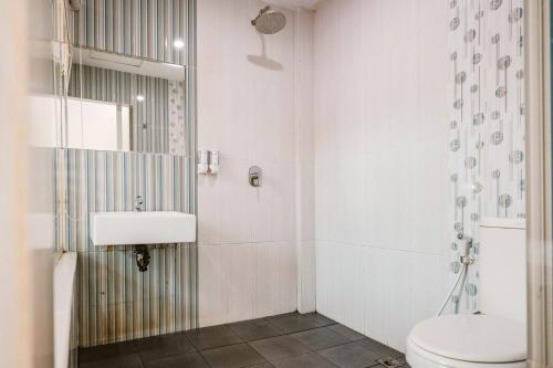 a white bathroom with a toilet and a sink at RedDoorz Premium at Hotel T-ONE Jambi in Tanjungjohor