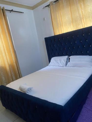 a bed with a black headboard and white sheets at SK Cosy Homes in Mombasa