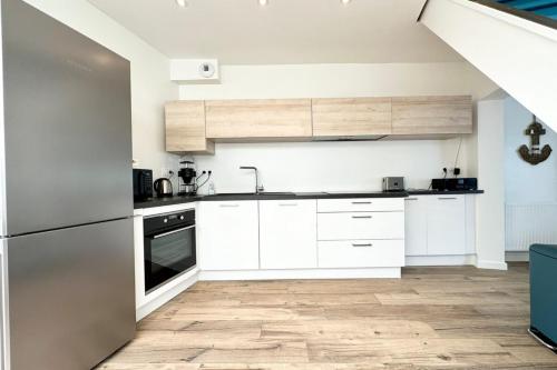a kitchen with white cabinets and a wooden floor at Maison de pêcheur Rénovée À 50m des plages in Riantec