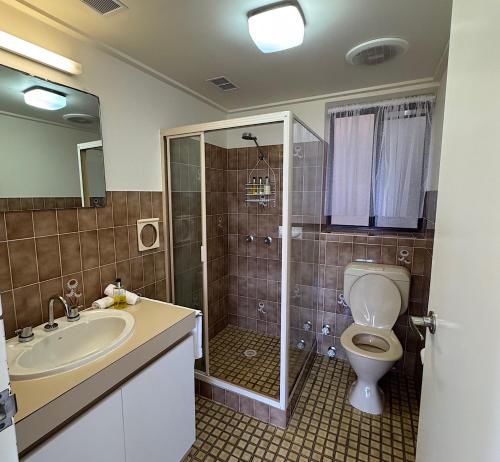 a bathroom with a toilet and a sink and a shower at Narooma Palms Holiday Apartments in Narooma