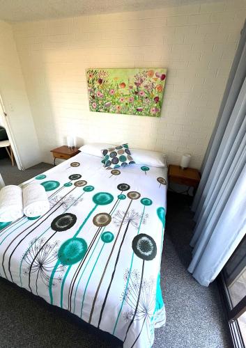 a bedroom with a bed with a colorful comforter at Narooma Palms Holiday Apartments in Narooma