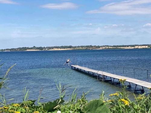 a person jumping off a dock into the water at House With A Beautiful View Of The Sea And Bogø in Stubbekøbing