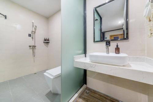 a bathroom with a sink and a toilet and a mirror at 泊汀酒店广州北京路步行街省中医店 in Guangzhou