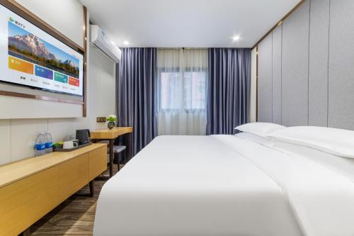 a hotel room with a bed and a flat screen tv at 泊汀酒店广州北京路步行街省中医店 in Guangzhou