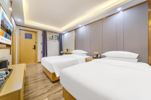 a hotel room with two beds and a television at 泊汀酒店广州北京路步行街省中医店 in Guangzhou