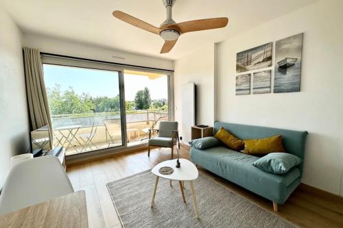 a living room with a blue couch and a large window at T2 refait à neuf À 2 pas du bourg et des plages in Larmor-Plage