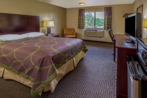 a hotel room with a bed and a flat screen tv at Super 8 by Wyndham Woodburn in Woodburn