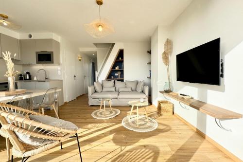 un salon avec un canapé et une télévision sur un mur dans l'établissement Magnifique ! T3 les pieds dans l’eau vue mer, à Ploemeur
