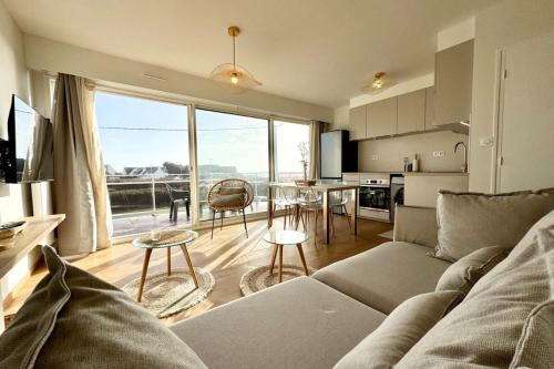 un salon avec un canapé et une table et une cuisine dans l'établissement Magnifique ! T3 les pieds dans l’eau vue mer, à Ploemeur