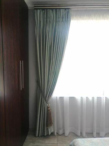 a curtain in a bedroom with a window at Silken Trap Accommodation NO LOADSHEDDING in Johannesburg