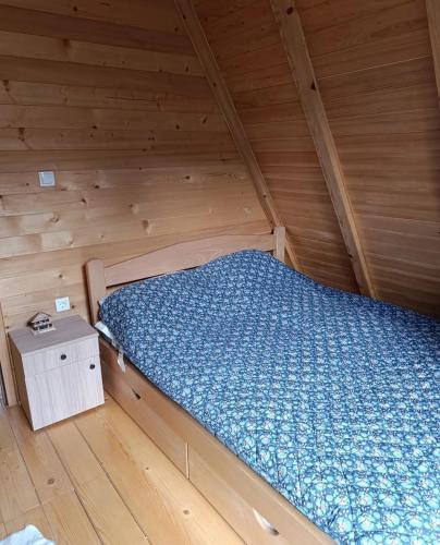a bed in a wooden cabin with a wooden floor at Planinska kuća Stašević in Mitrovac