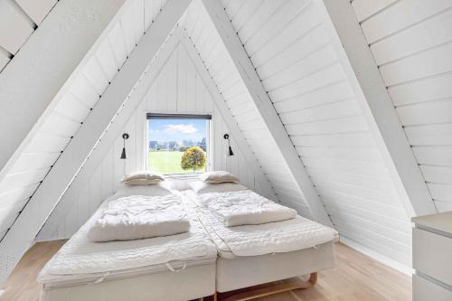 ein Schlafzimmer mit einem Bett im weißen Dachgeschoss in der Unterkunft Summer House At Himmerland Golf Resort in Farsø