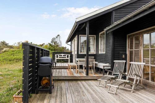 a black house with chairs and a grill on a deck at Welcoming Holiday Home Right Down To The Water in Rørvig