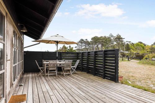 a wooden deck with a table and an umbrella at Welcoming Holiday Home Right Down To The Water in Rørvig