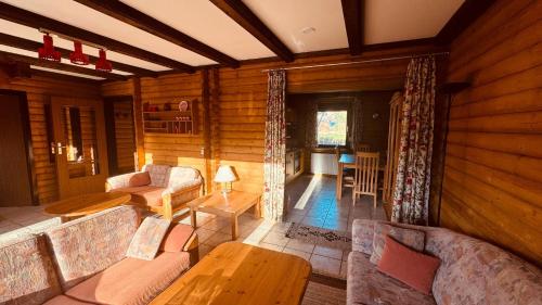 a living room of a log cabin with couches and a table at Ferienwohnung Sonnenblick in Arrach in Arrach