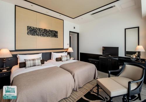 a hotel room with two beds and a chair at Hotel Monterey Okinawa Spa & Resort in Onna