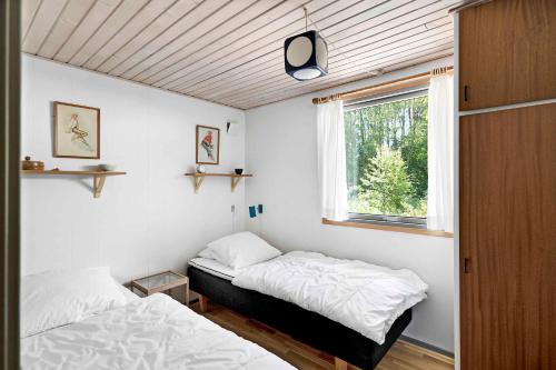 two beds in a small room with a window at Cottage In Peaceful Surroundings In Vester Sømark in Vester Sømarken