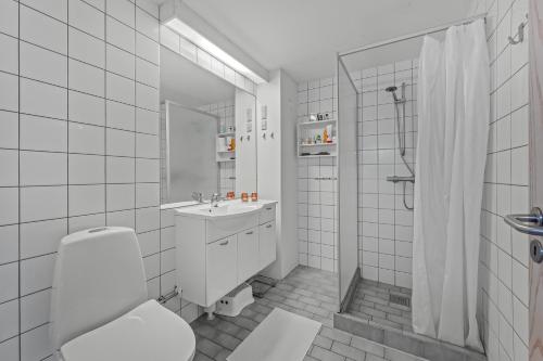 a white bathroom with a toilet and a sink at Cozy Holiday Apartment In The Center Of Søndervig Close To The North Sea in Ringkøbing