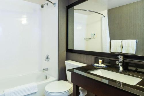 a bathroom with a toilet and a sink and a mirror at Comfort Inn Hwy 401 in Kingston