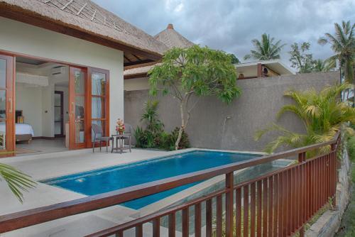 a villa with a swimming pool next to a house at Anusara Luxury Villas in Ubud