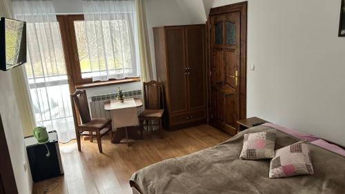 a bedroom with a bed and a table and a sink at Gospodarstwo agroturystyczne Bustrycki in Poronin
