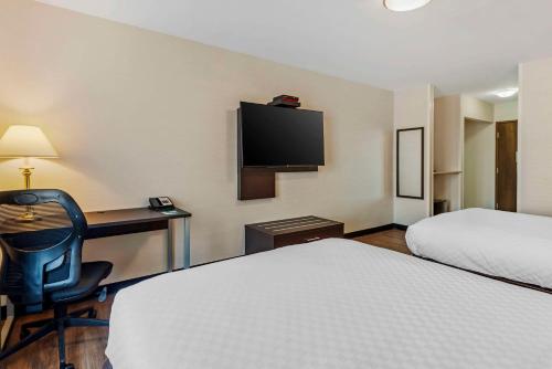 a hotel room with two beds and a desk and a television at Quality Inn in Ottawa