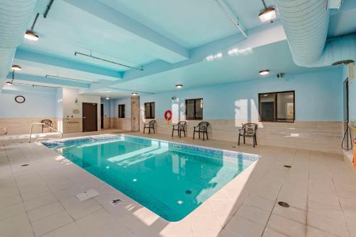 a large pool in a large room with chairs and tables at Quality Inn in Ottawa