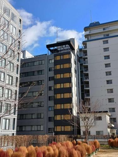 a tall building in front of two tall buildings at 天満橋 Guest House#有电梯 #步行大阪城 #赏樱花必打卡点 #直达梅田 京都 #免费wifi in Osaka