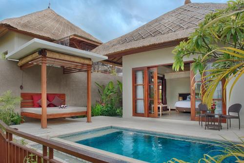 a villa with a swimming pool and a bedroom at Anusara Luxury Villas in Ubud