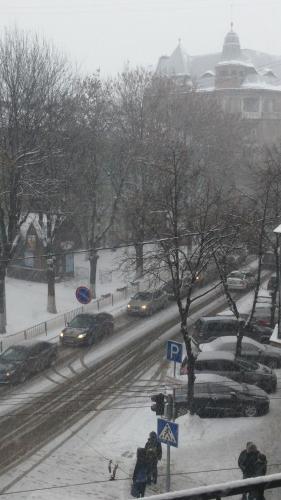 a city street covered in snow with cars at Aparthotel NA DOBU in Lviv
