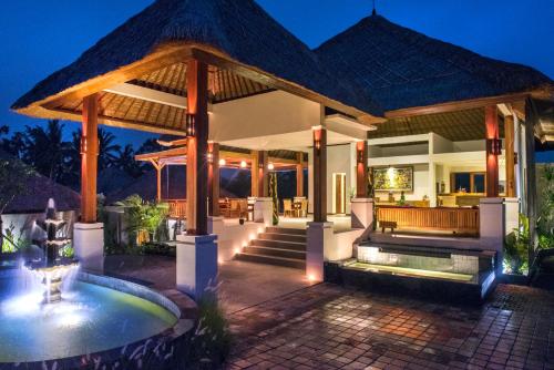 a villa with a swimming pool at night at Anusara Luxury Villas in Ubud