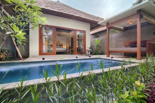 a villa with a swimming pool in front of a house at Anusara Luxury Villas in Ubud