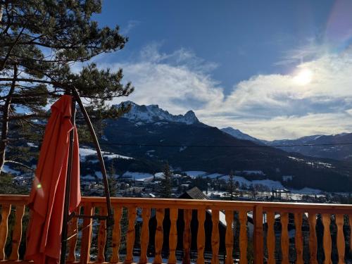 an orange umbrella sitting on a deck with a view of mountains at Chalet avec Spa Magnifique vue in Barcelonnette