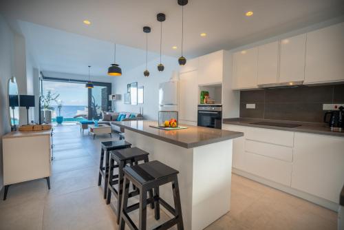 a kitchen with white cabinets and a island with bar stools at Oceanfront Oasis with Private Pool Stunning Views in Kérynia