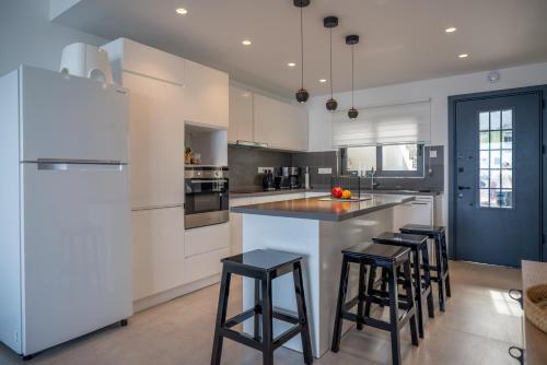 a kitchen with white cabinets and black bar stools at Oceanfront Oasis with Private Pool Stunning Views in Kérynia