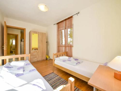 a bedroom with two beds and a table and a window at Apartments Angelina - 2min to the beach in Karlobag