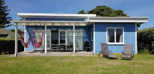 a blue house with a table and chairs in a yard at Kapiti Seaside Magic in Paraparaumu