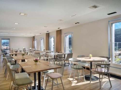 インスブルックにあるHilton Garden Inn Innsbruck Tivoliのテーブルと椅子と窓のあるレストラン