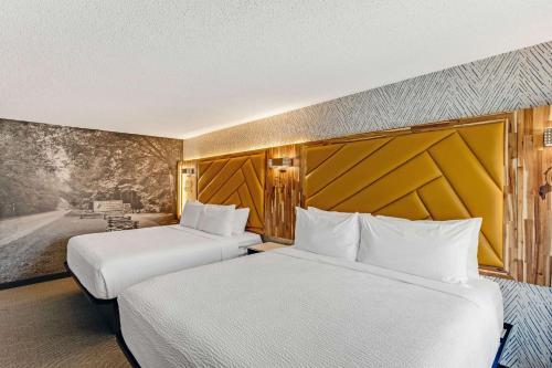two beds in a hotel room with white sheets at The Wander Hotel in Gatlinburg