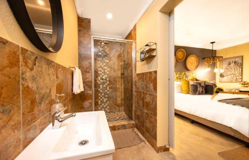 a bathroom with a sink and a shower and a bed at Zabini Lodge and Game Drives in Nelspruit