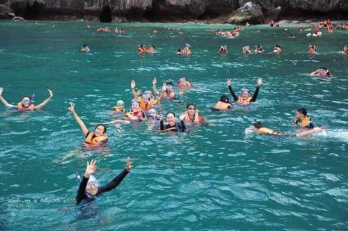 a group of people swimming in the water at DD Beach Houses in Phra Ae beach