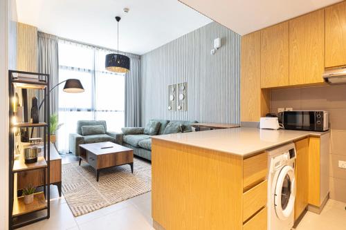 a kitchen and a living room with a couch at شقة رائعة بغرفة نوم واحدة وصالة في الممشى - The Sapphire in Sharjah