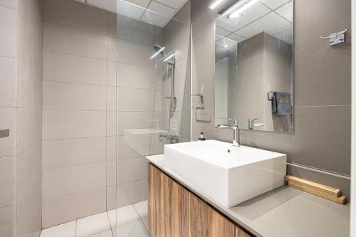 a bathroom with a white sink and a shower at شقة رائعة بغرفة نوم واحدة وصالة في الممشى - The Sapphire in Sharjah