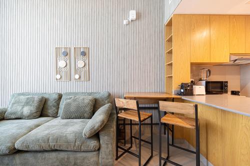 a living room with a couch and a kitchen at شقة رائعة بغرفة نوم واحدة وصالة في الممشى - The Sapphire in Sharjah