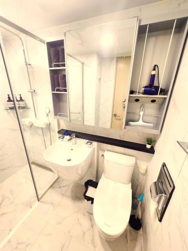 a white bathroom with a toilet and a sink at Majestic Seoul Stay Central in Seoul