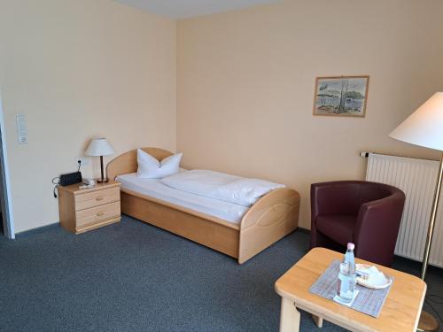 a hotel room with a bed and a chair and a table at Hotel Heikenberg in Bad Lauterberg