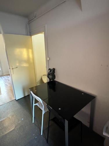 - une table noire et une chaise blanche dans la chambre dans l'établissement Maison de ville parking privé, à Bourges