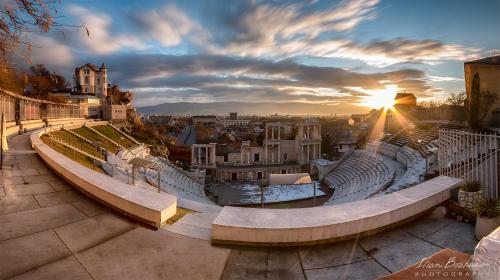 a view of a city at sunset with benches at Noviz Hotel in Plovdiv